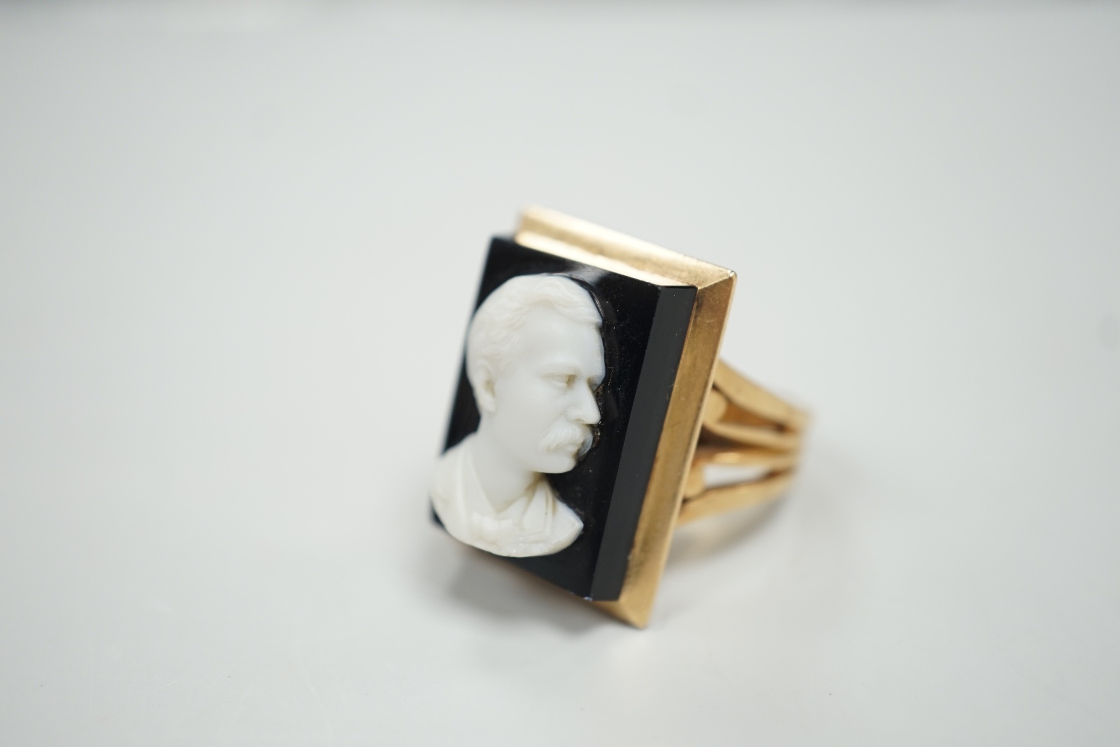 A yellow metal and black sardonyx set rectangular cameo ring, carved with the bust of a gentleman to sinister, size L, gross weight 12.6 grams.